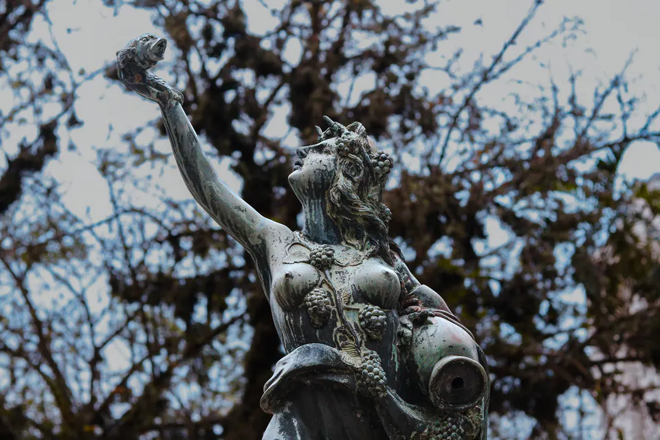 estátua de bronze erguendo um peixe contra os galhos
