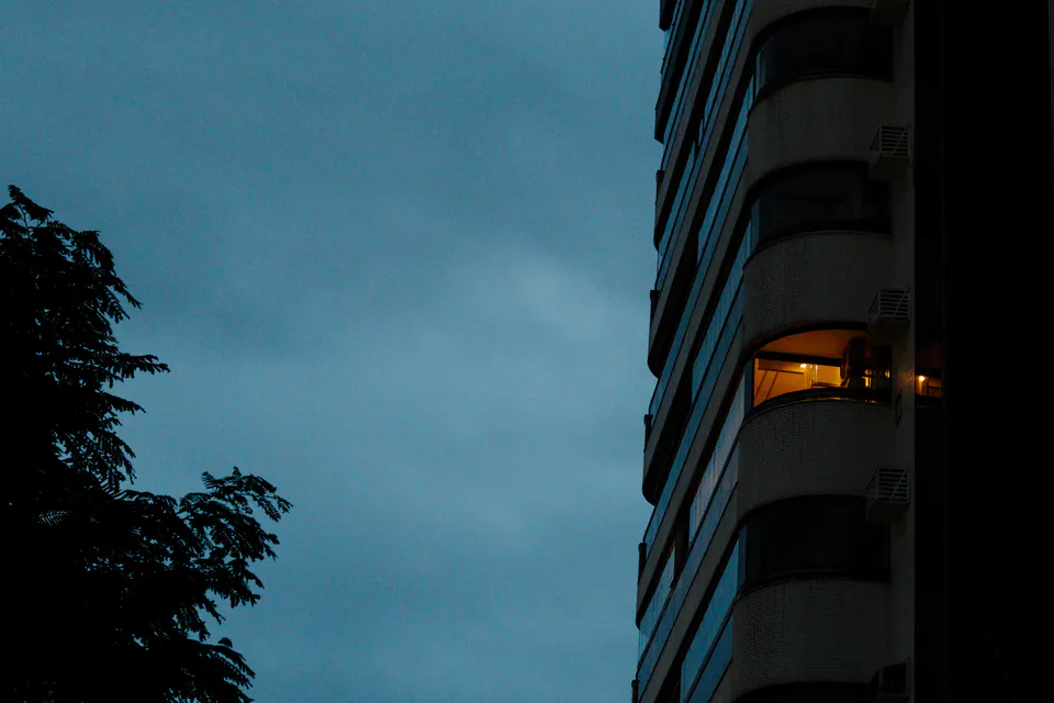prédio com janelas acesas ao entardecer