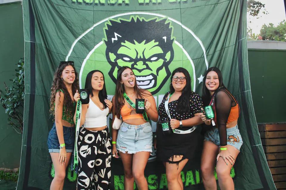 grupo de amigas diante do banner da atlética