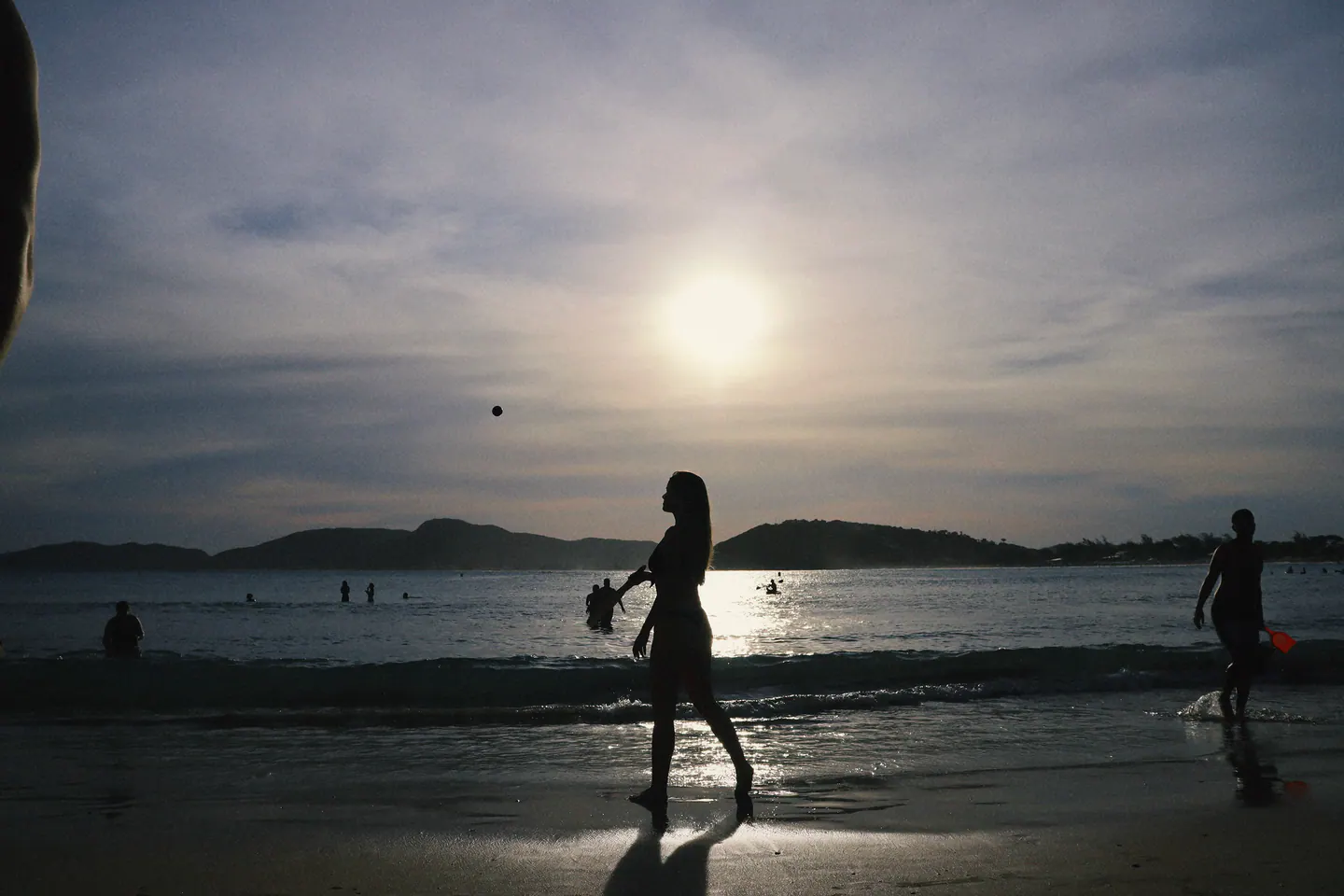 silhueta caminhando na beira do mar contra o sol