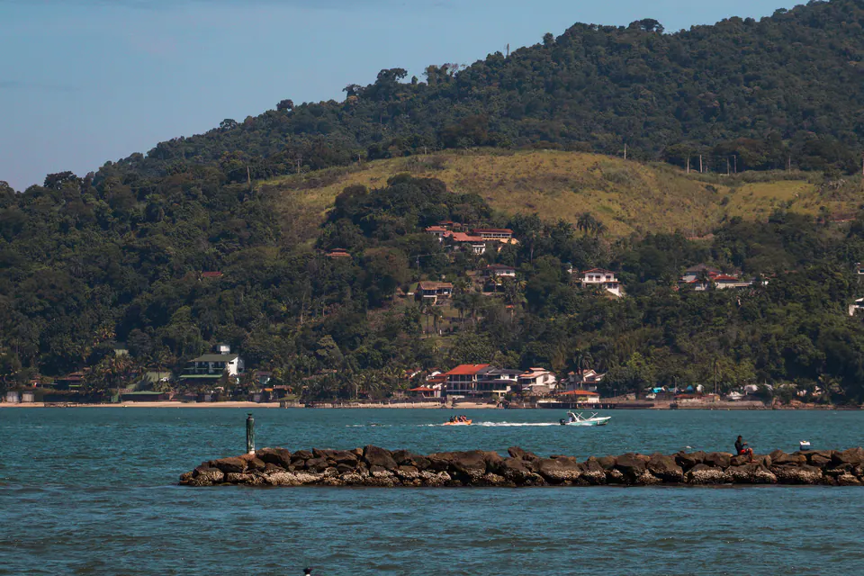 morro com casas e um quebra-mar na frente