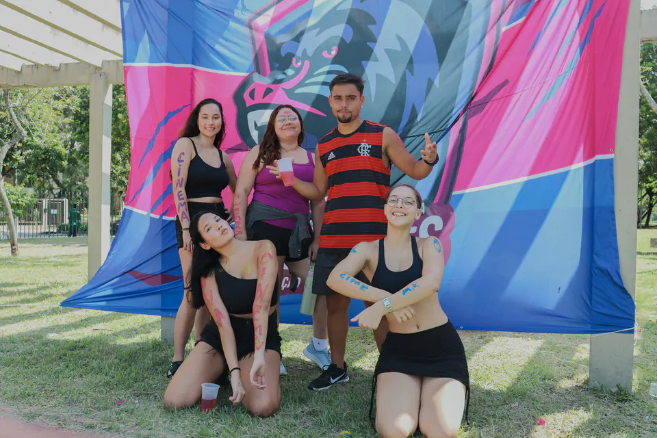 grupo de calouros posando em frente a uma bandeira rosa e azul