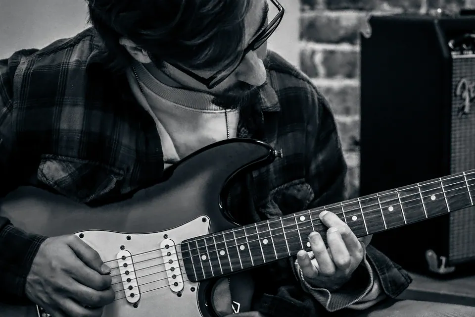 close em preto e branco das mãos no braço da guitarra