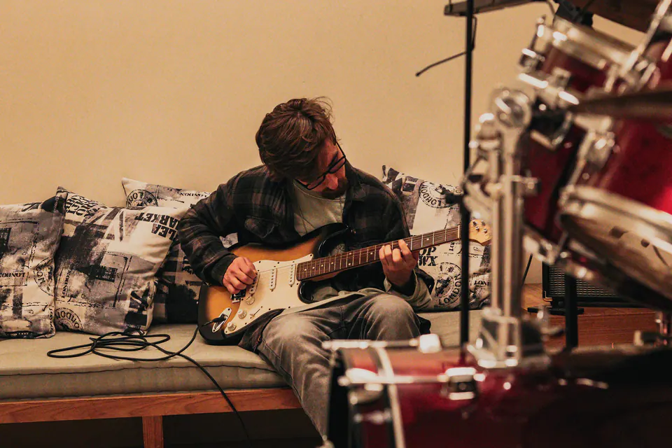 hugo motta tocando guitarra com a bateria vermelha em primeiro plano